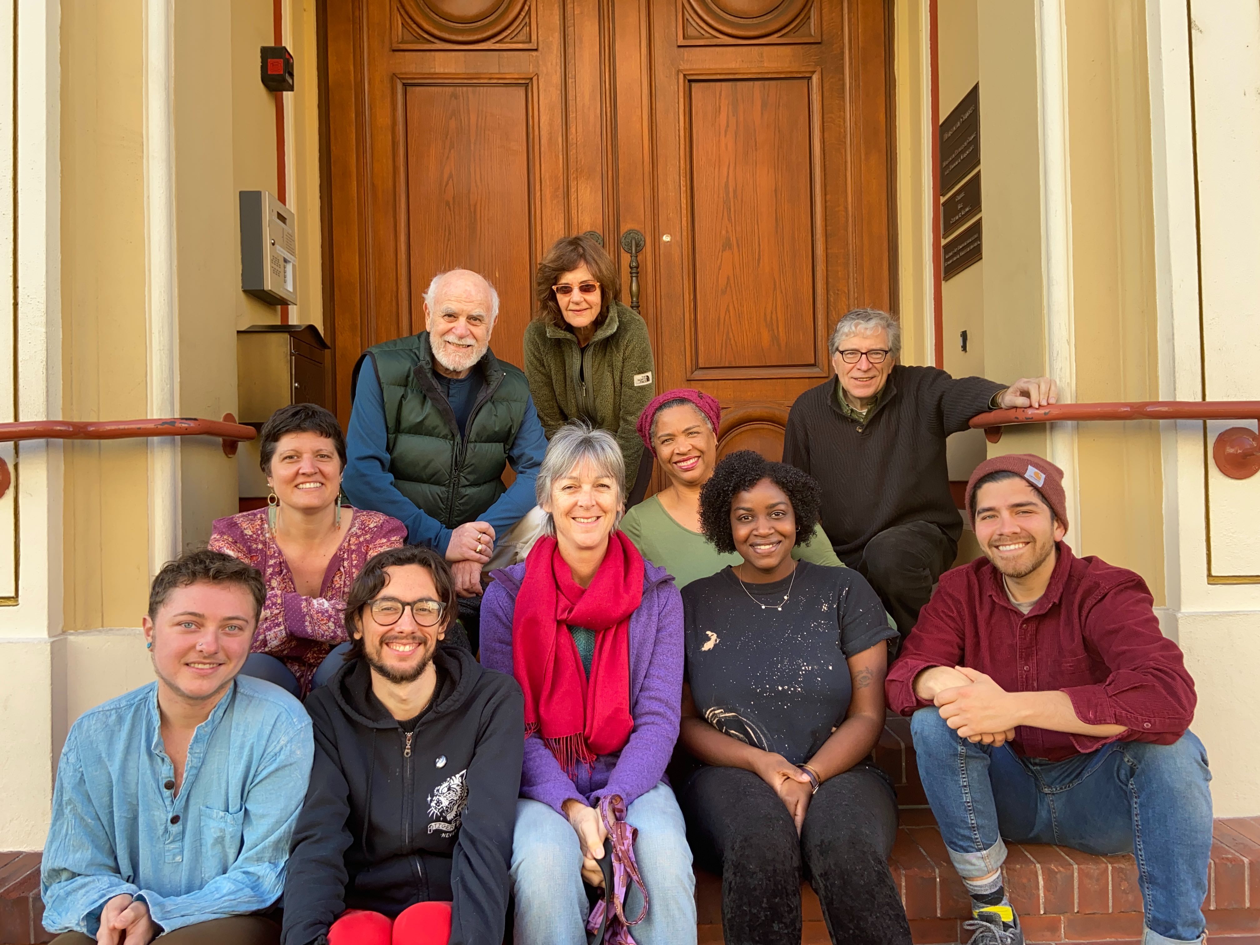 Diverse group of people smiling on steps outside Mangalam Center.