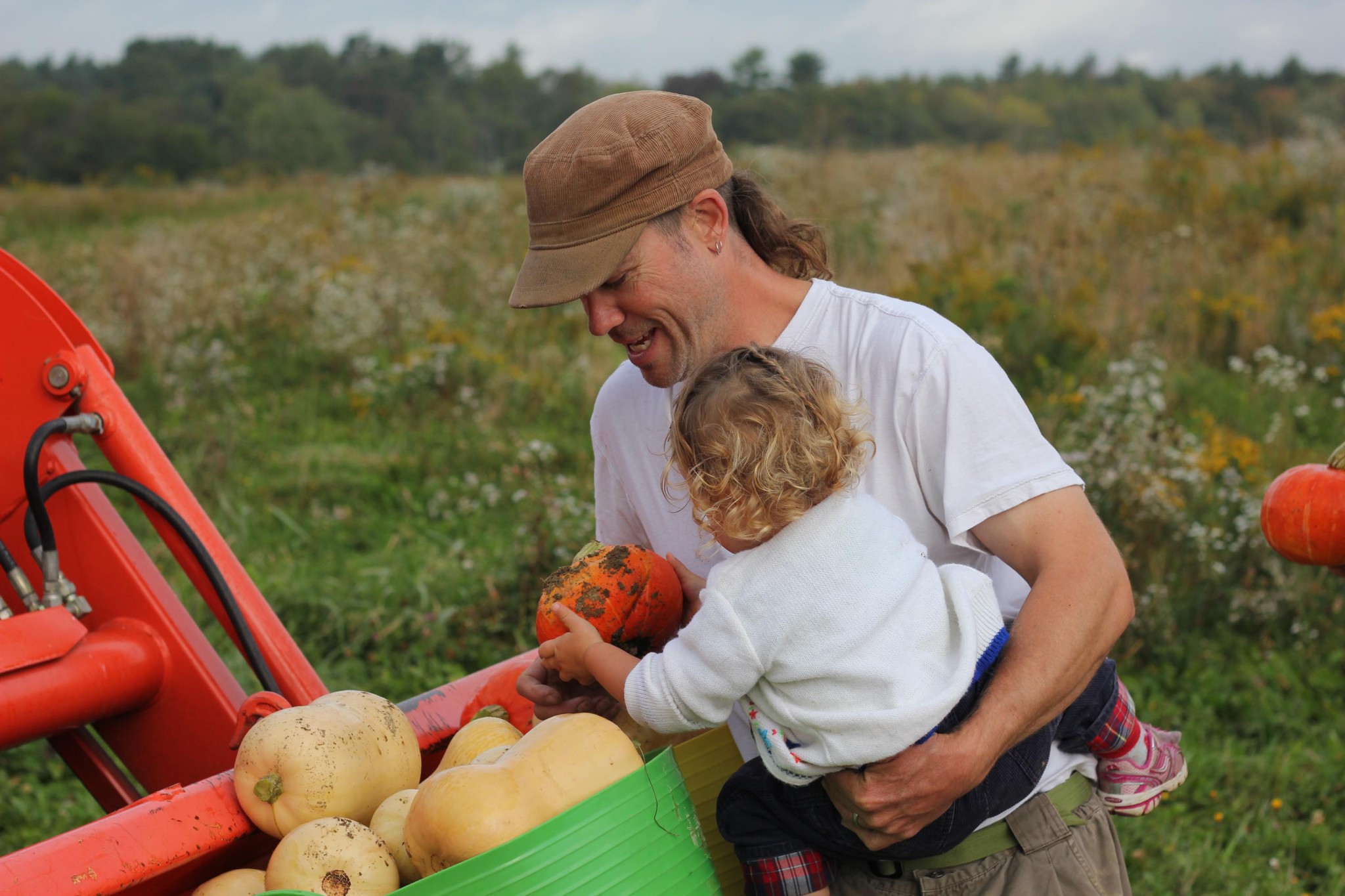 Family harvesting pumpkins in a community farm with lush greenery in the background.