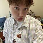 Person with short brown hair and green eyes in a casual shirt.