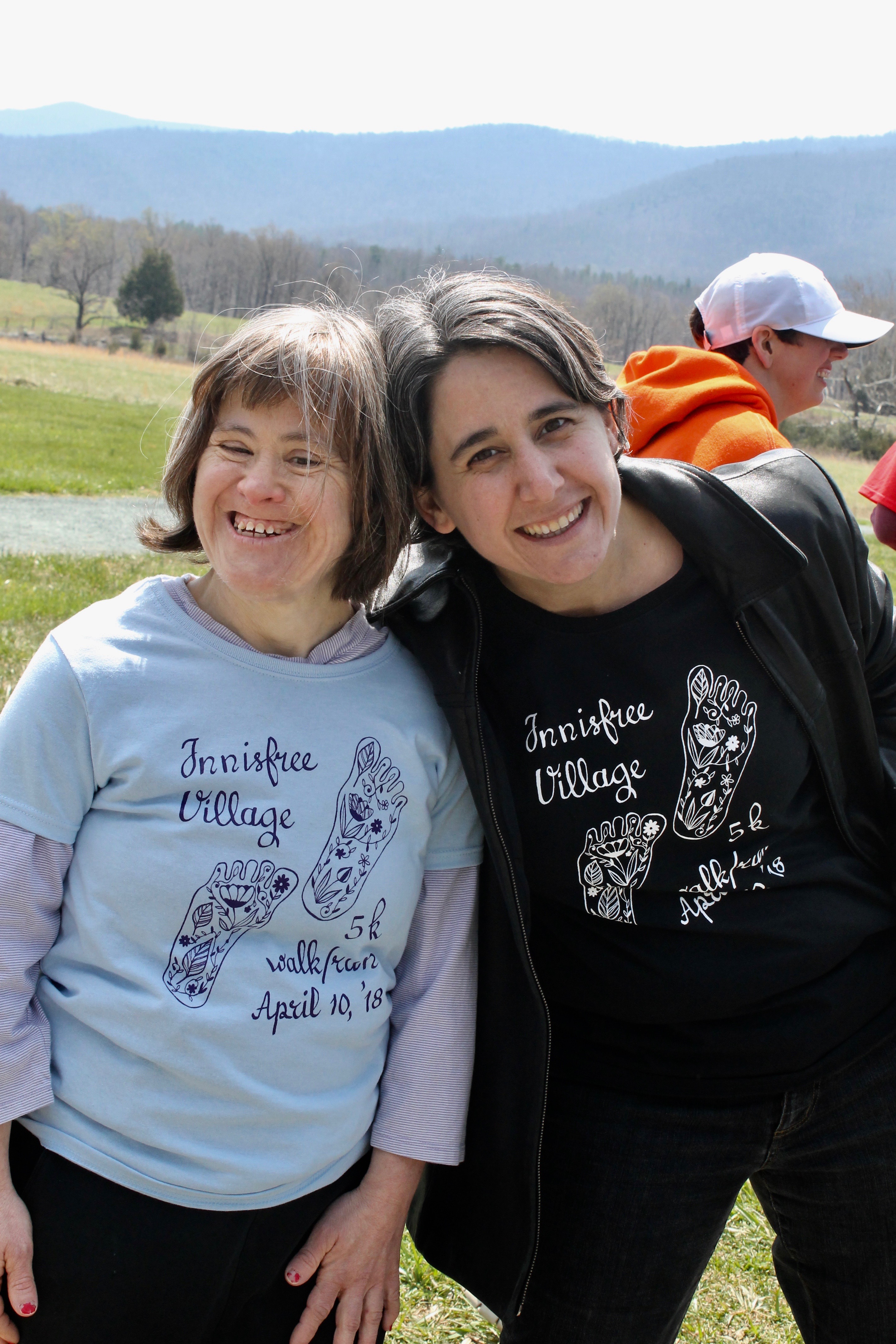 Smiling women at Innisfree Village outdoor gathering in scenic landscape.