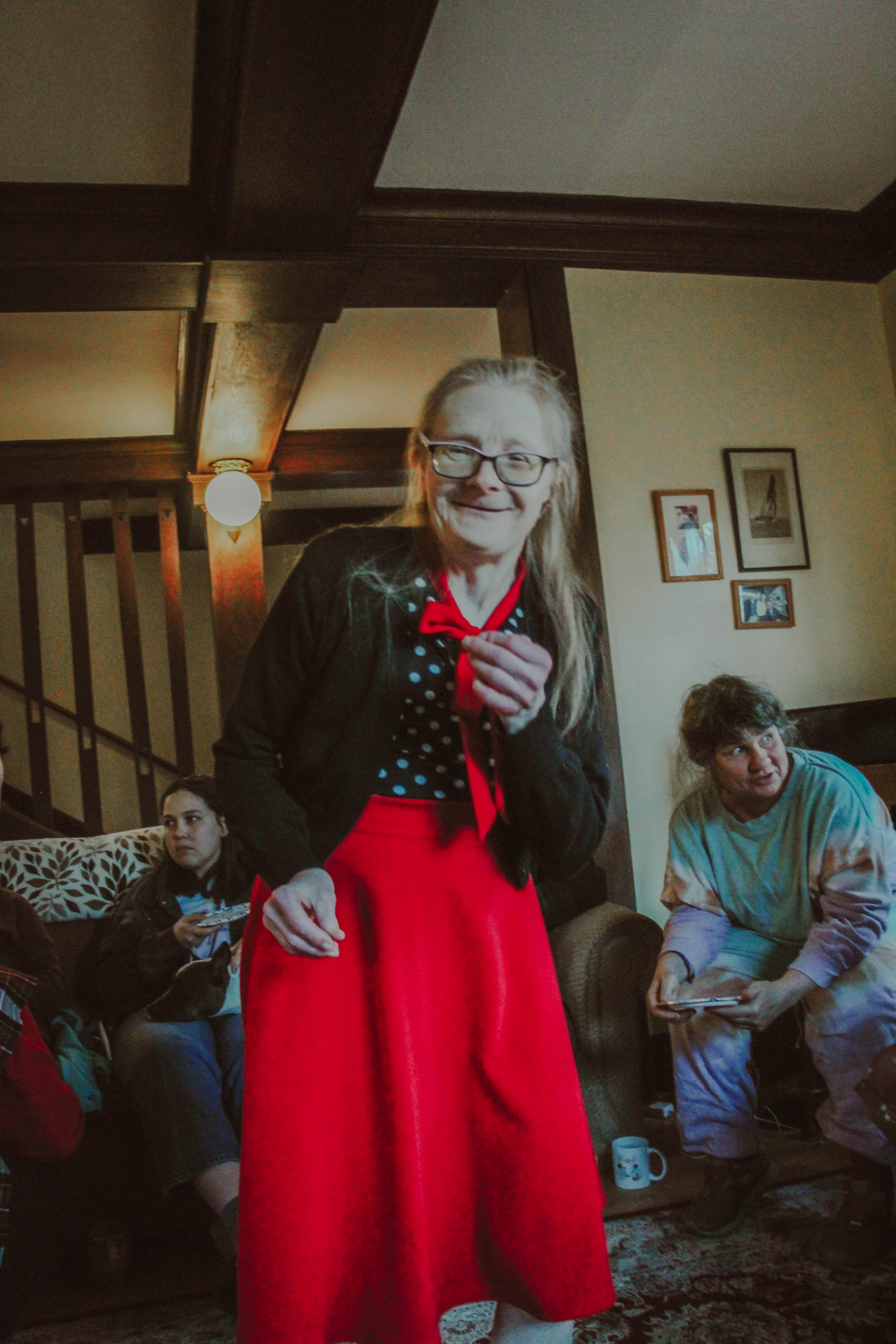 Woman in red skirt and glasses smiling at community event in L'Arche Seattle.