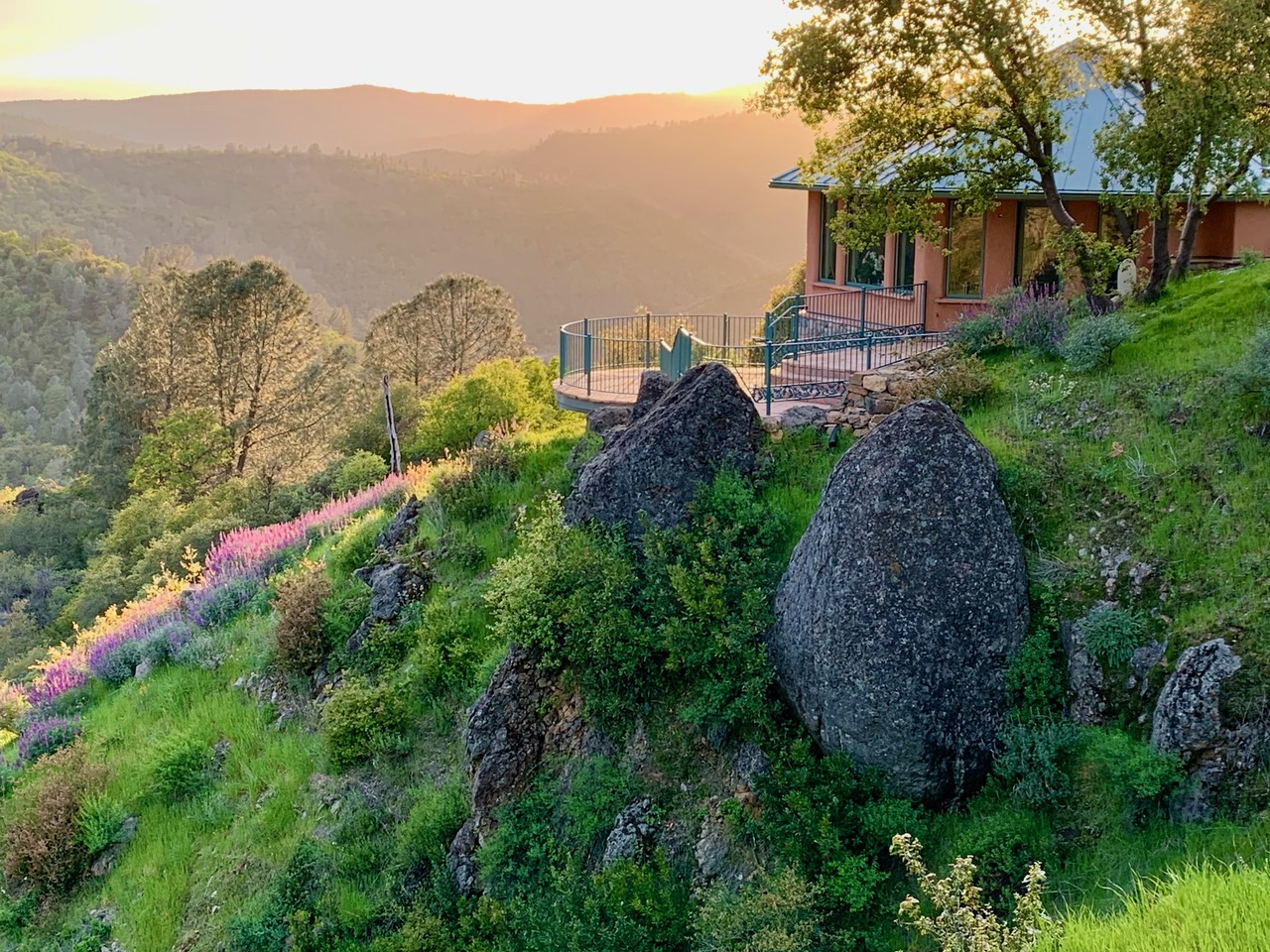 Scenic view of Wild Grace Community with house, rocks, and lush greenery.