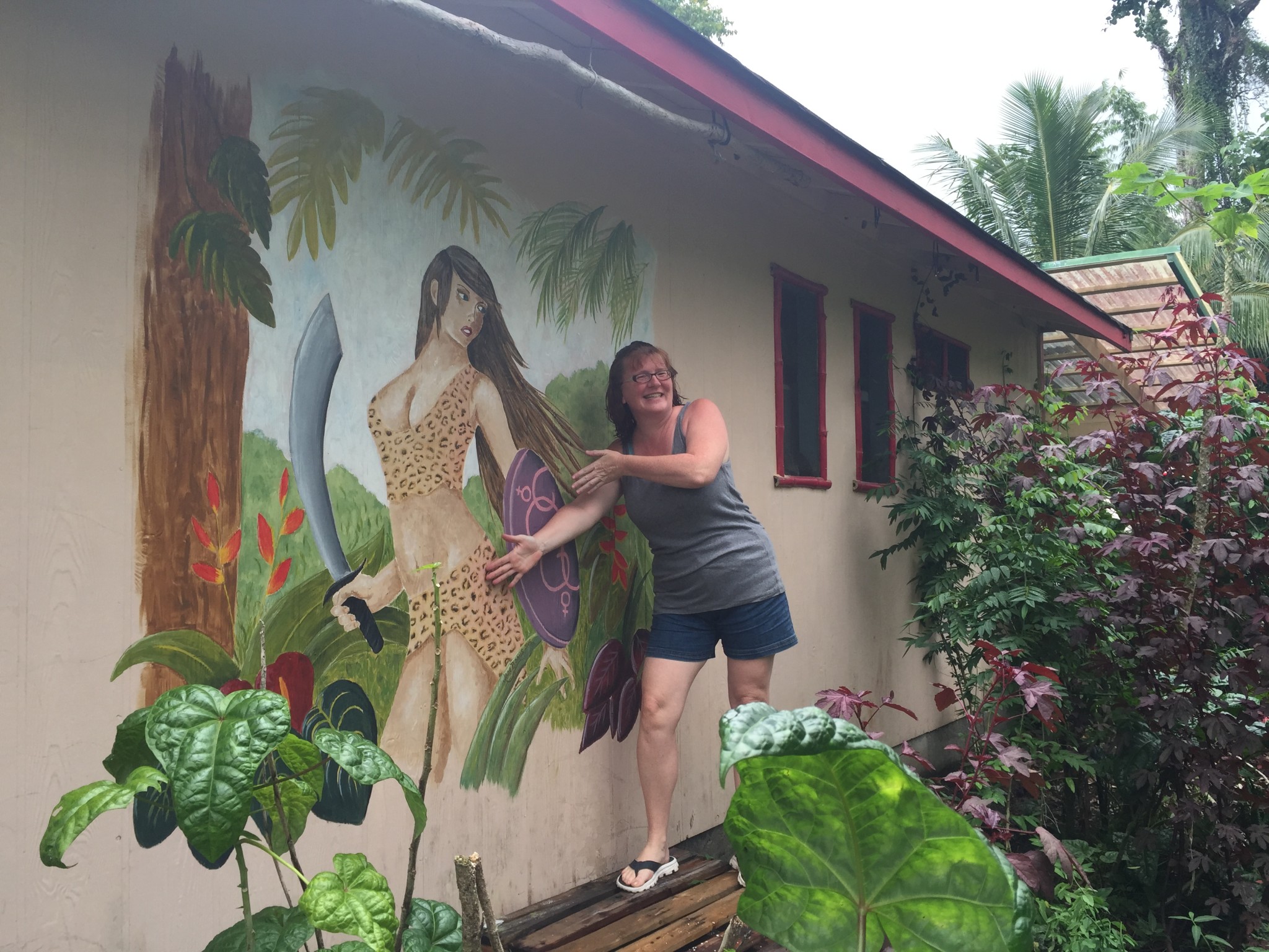 Woman smiling next to a jungle-themed mural at Hedonisia Hawaii.