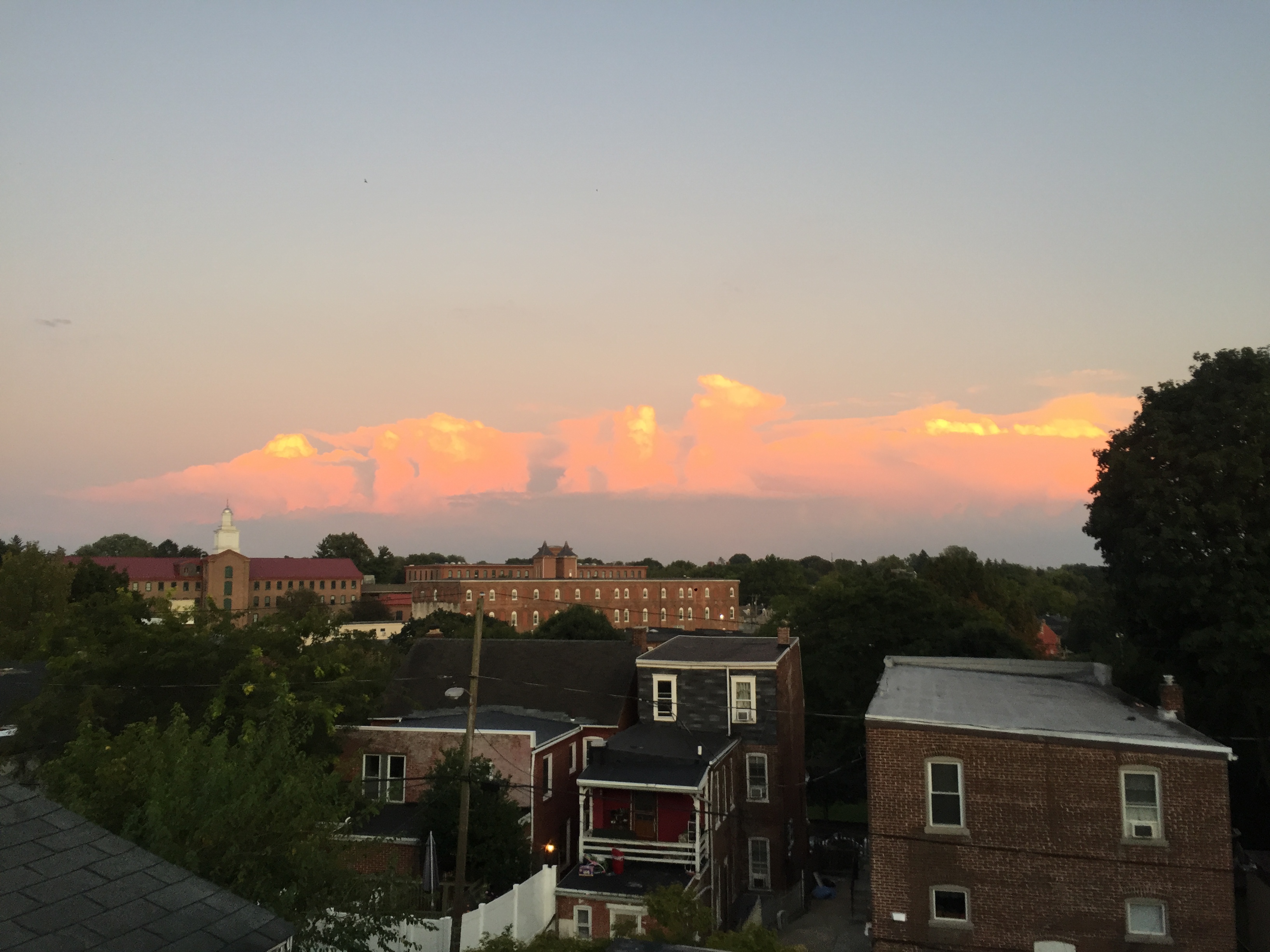 Sunset over community buildings with colorful clouds in the sky.