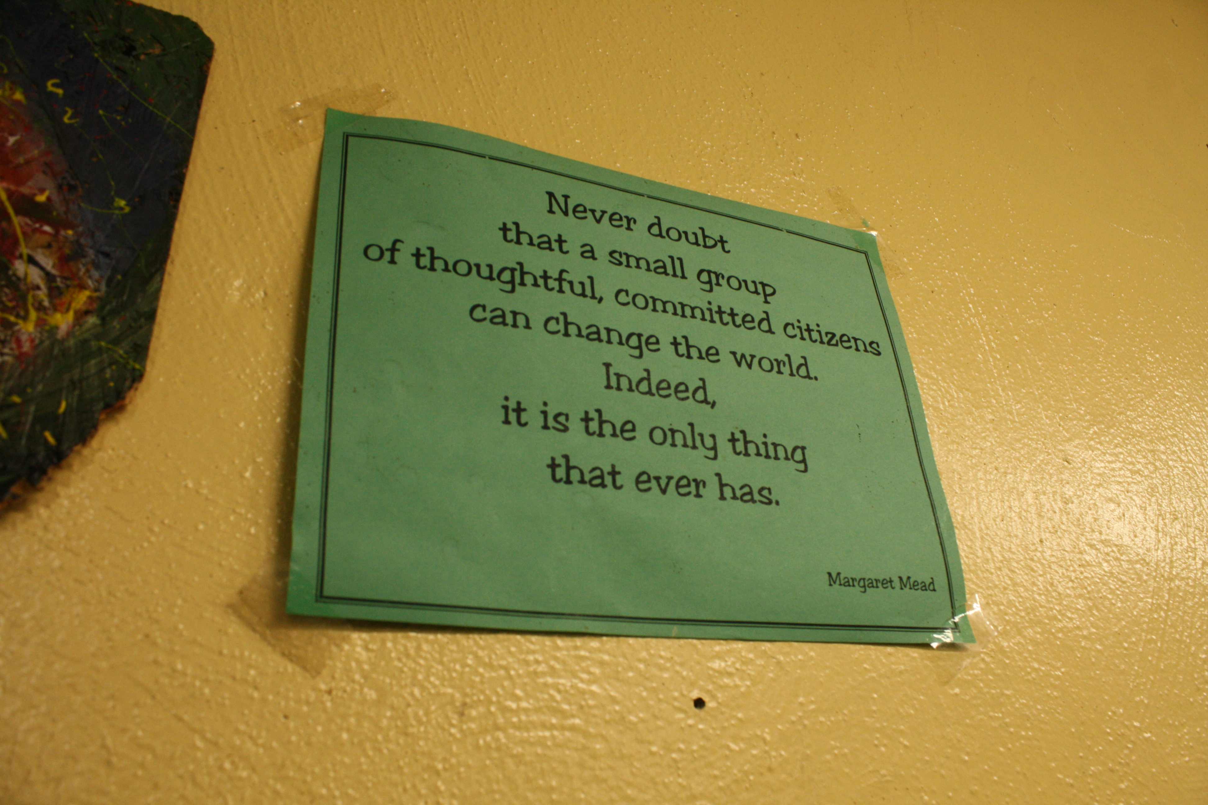 Green quote card with motivational message on a yellow wall.