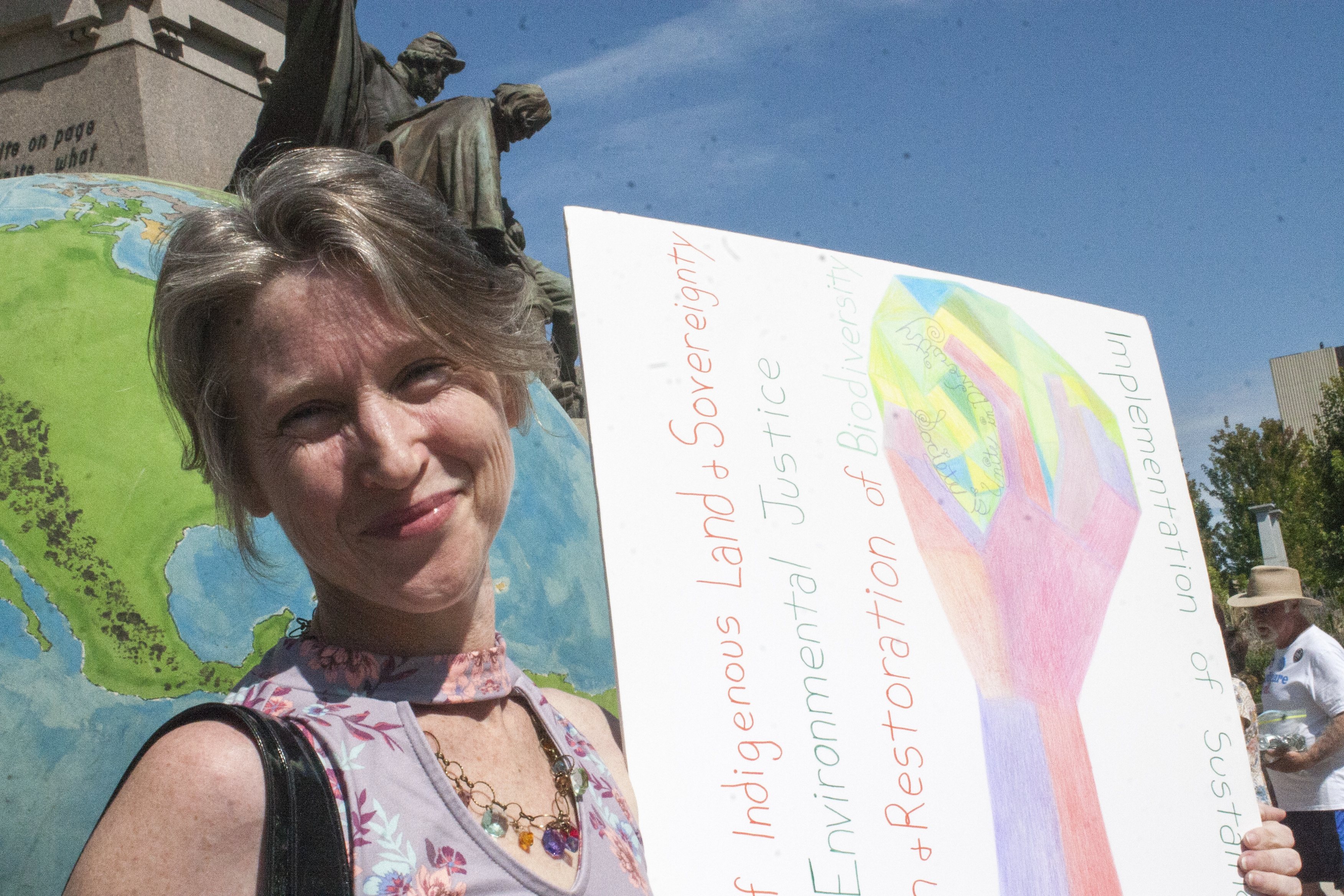 Woman at Indigenous Land and Environmental Justice protest holding a sign.