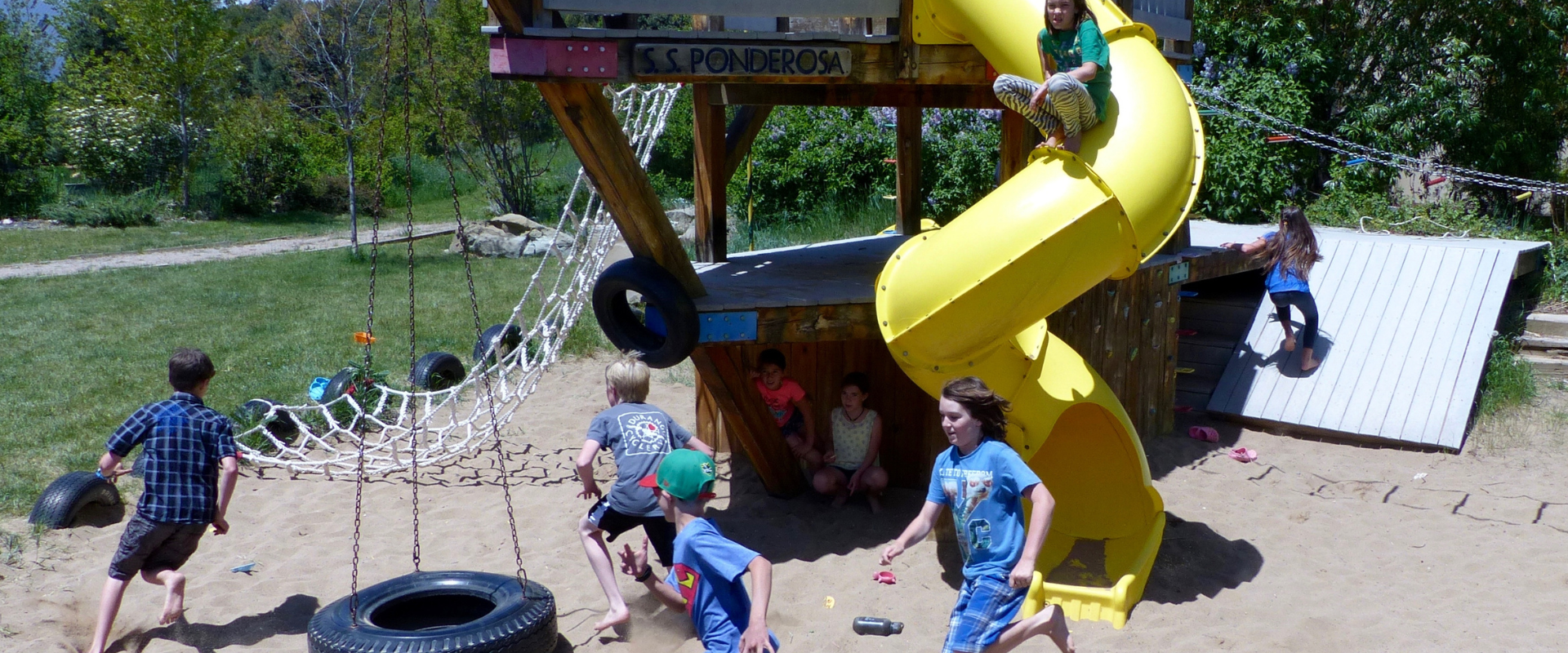 Kids enjoying outdoor play area with slide and swings at Heartwood Cohousing.