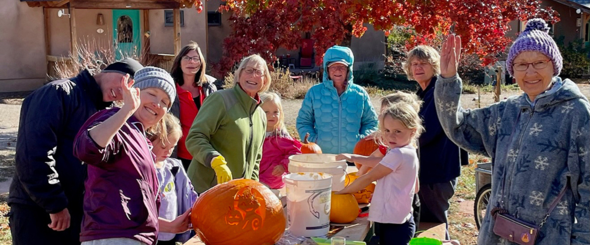 Group of diverse people carving pumpkins outdoors in autumn.