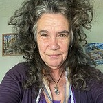 Portrait of a woman with curly gray hair and a warm smile.