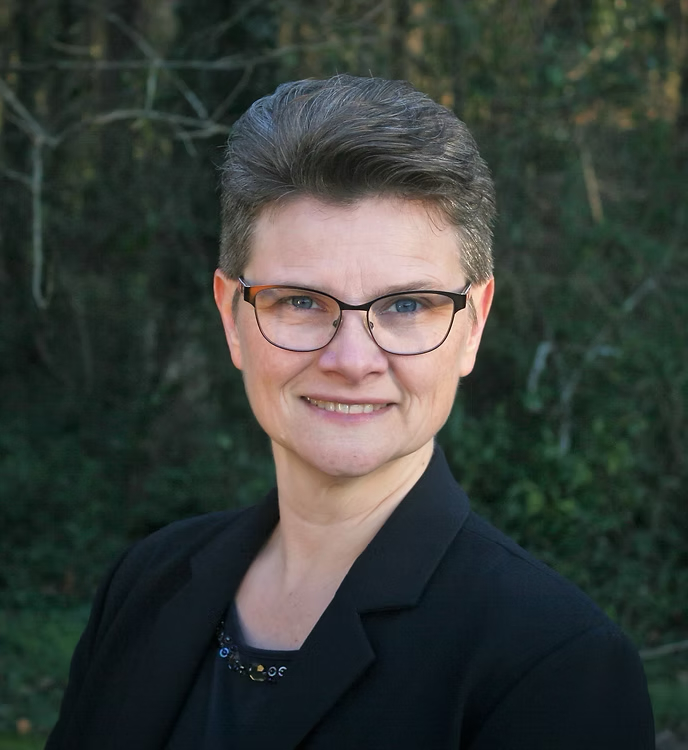 Portrait of a woman in professional attire outdoors for community building.