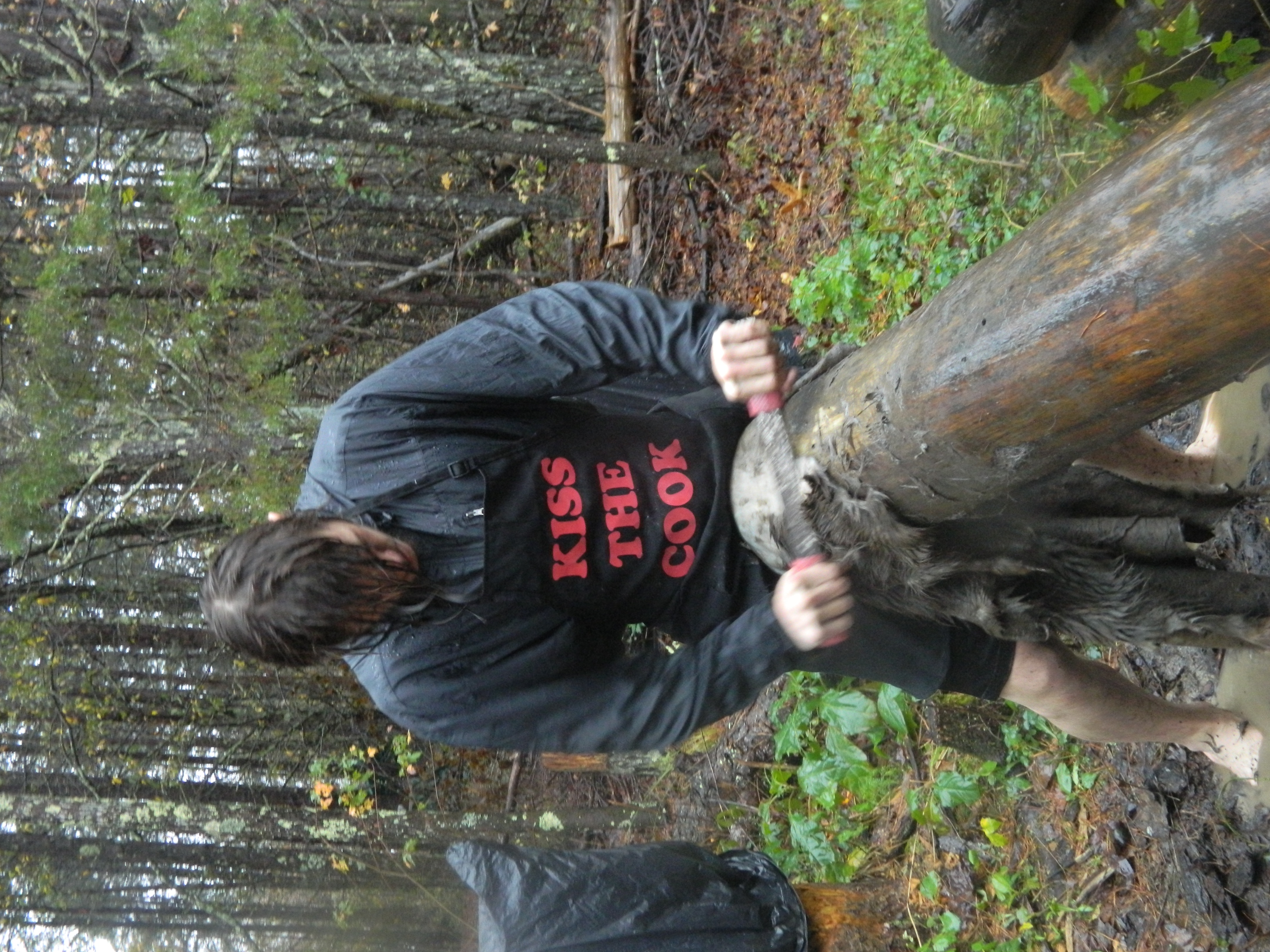 Person working on a wooden water collection system in a forest setting.