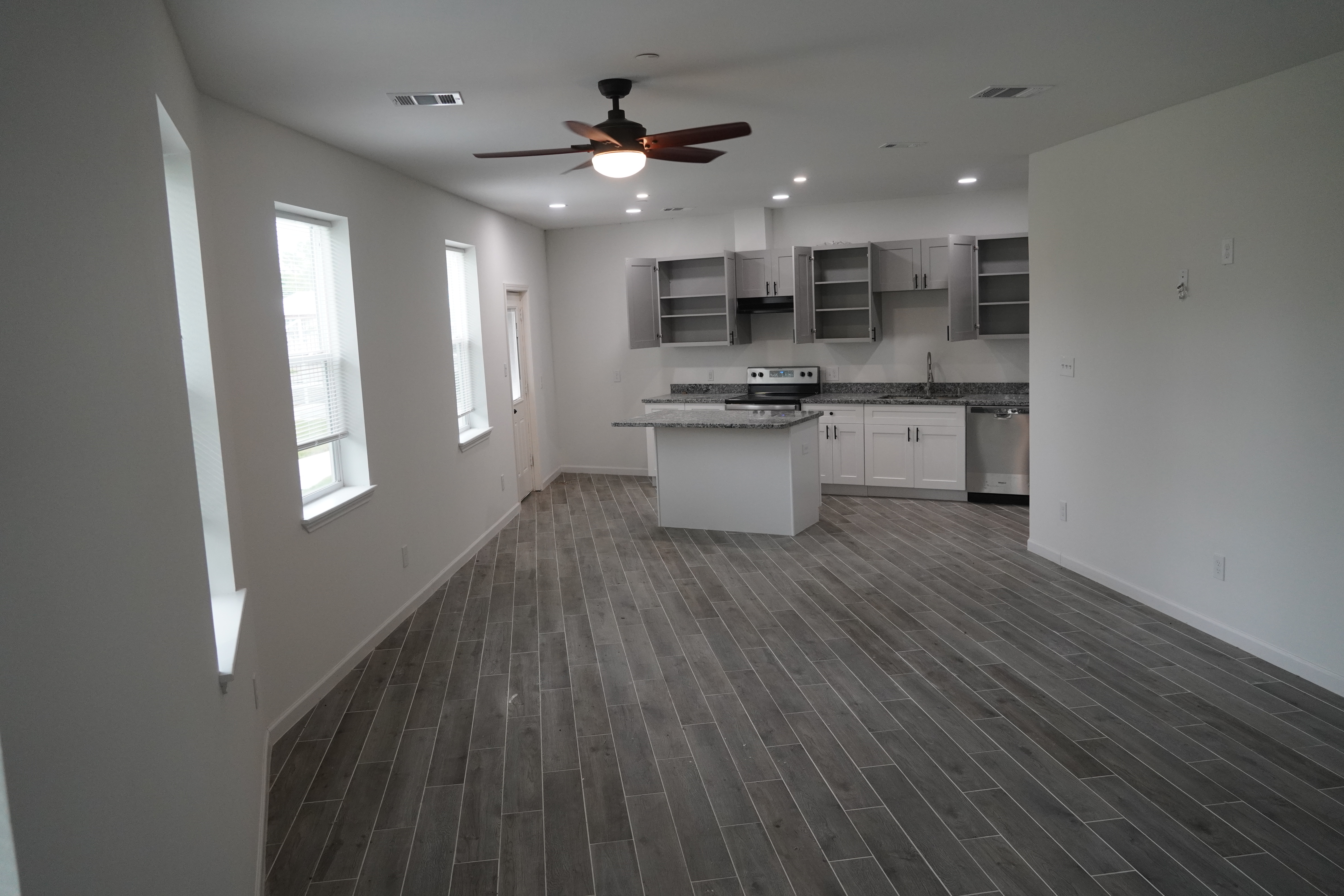 Spacious modern kitchen with white cabinets and gray flooring.