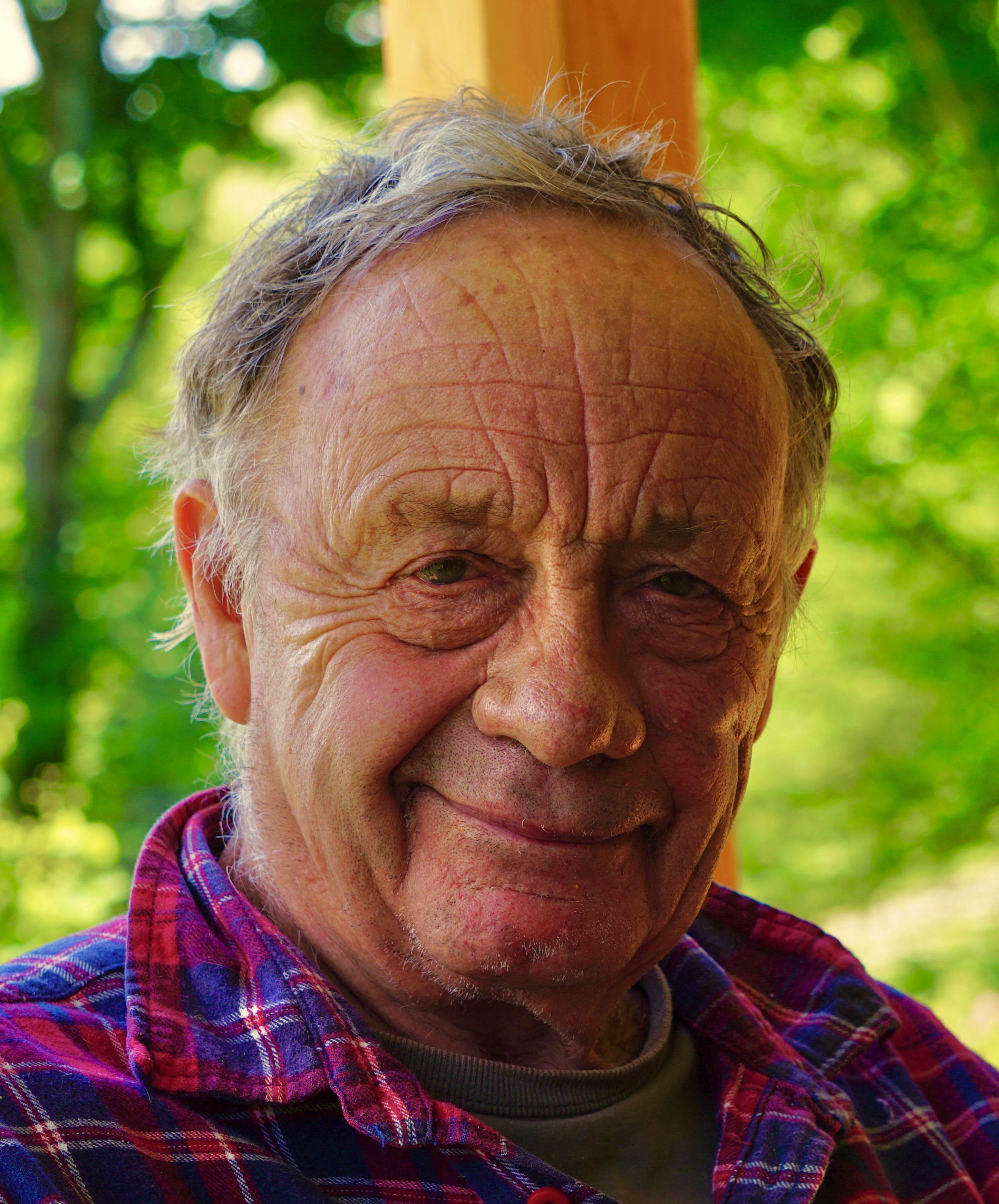 Smiling elderly man outdoors at Windekind intentional community.