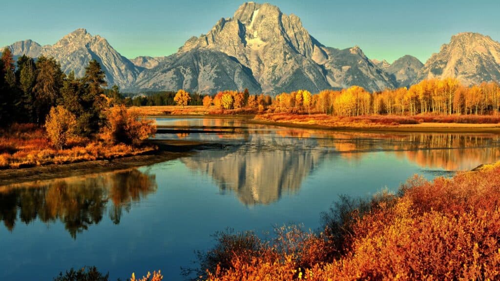 Majestic mountains reflected in a calm river during autumn.