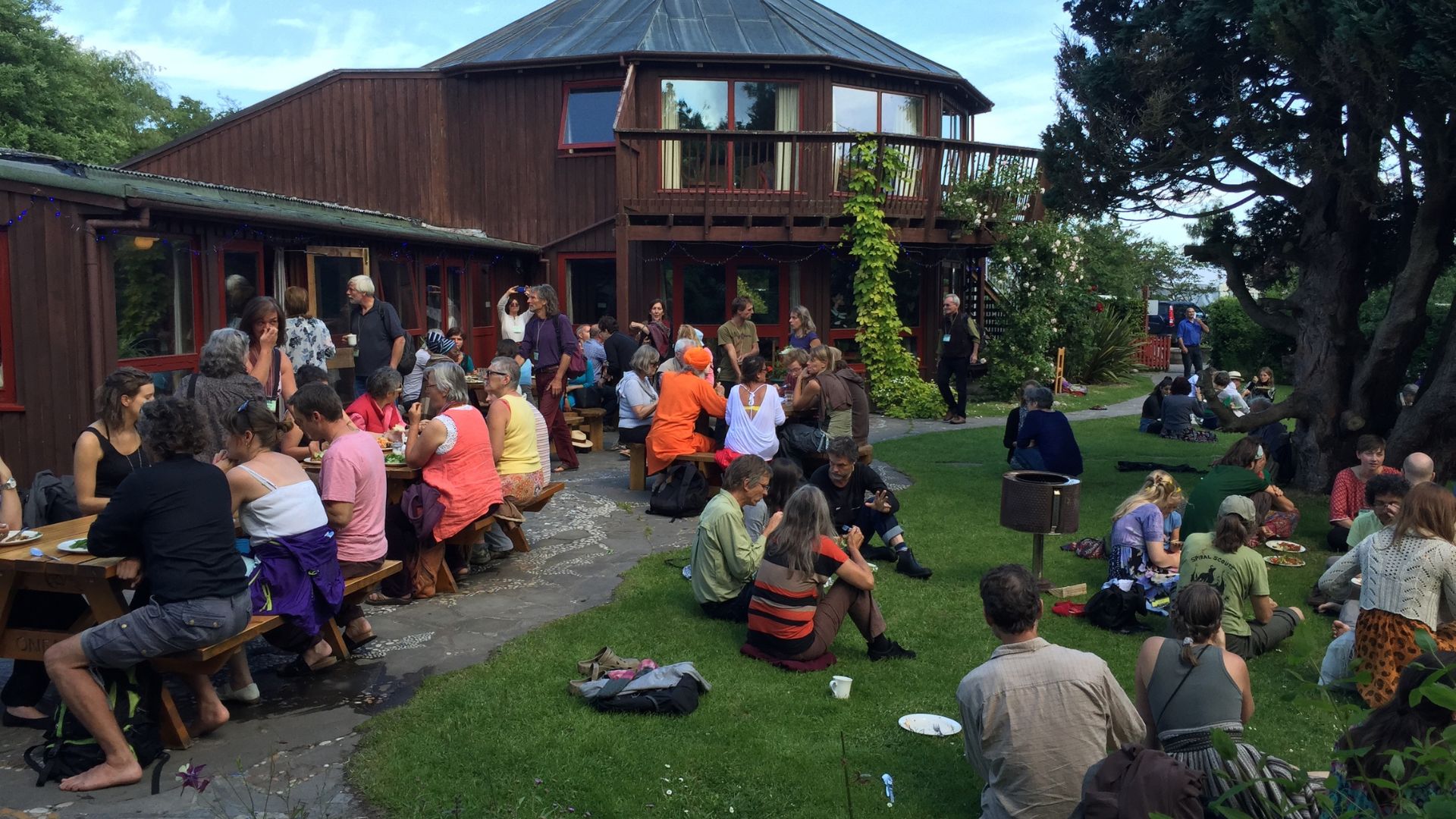 People gathered outdoors at a community event near a wooden building.