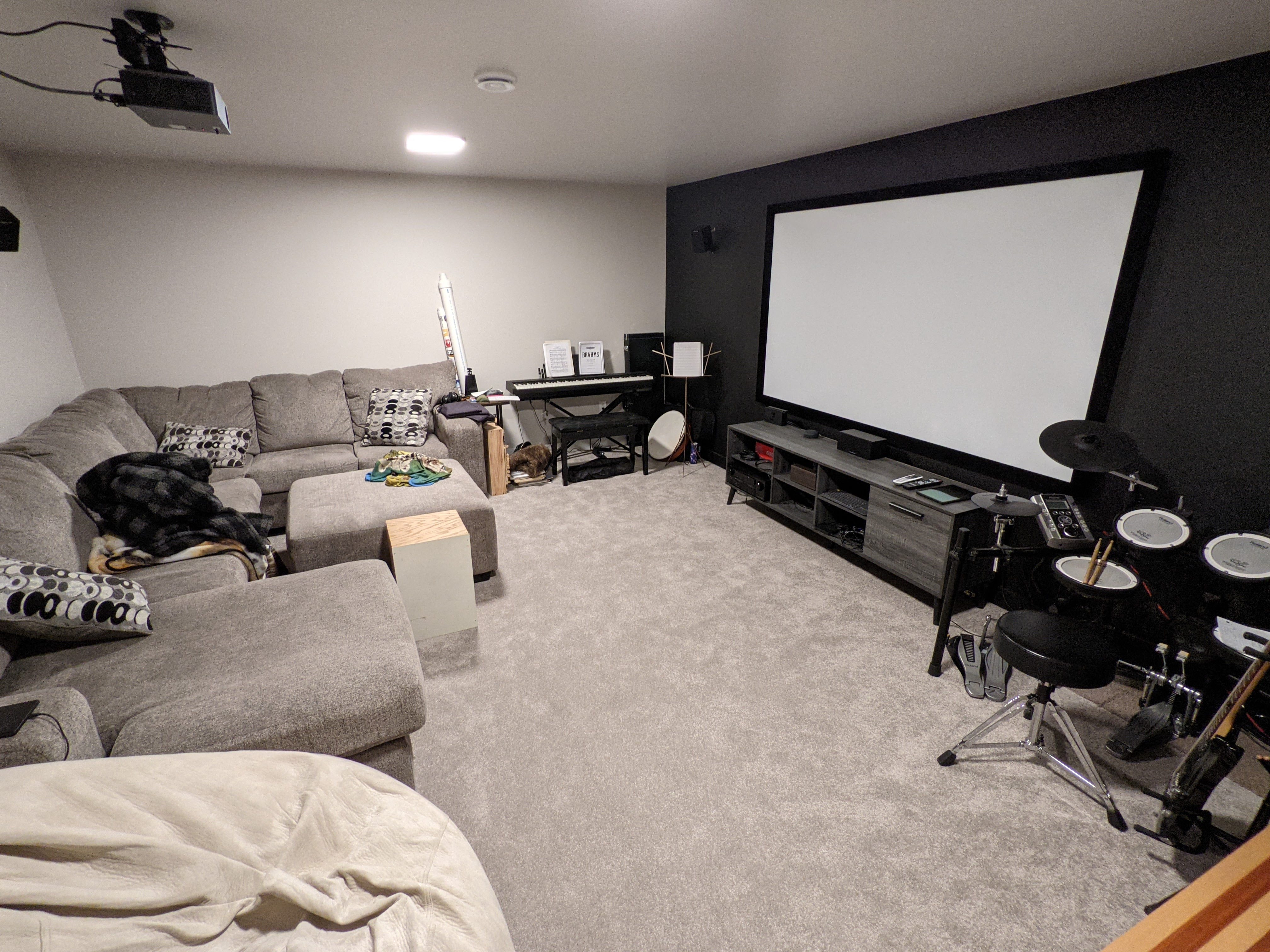 Cozy home theater with large screen and musical instruments in the corner.