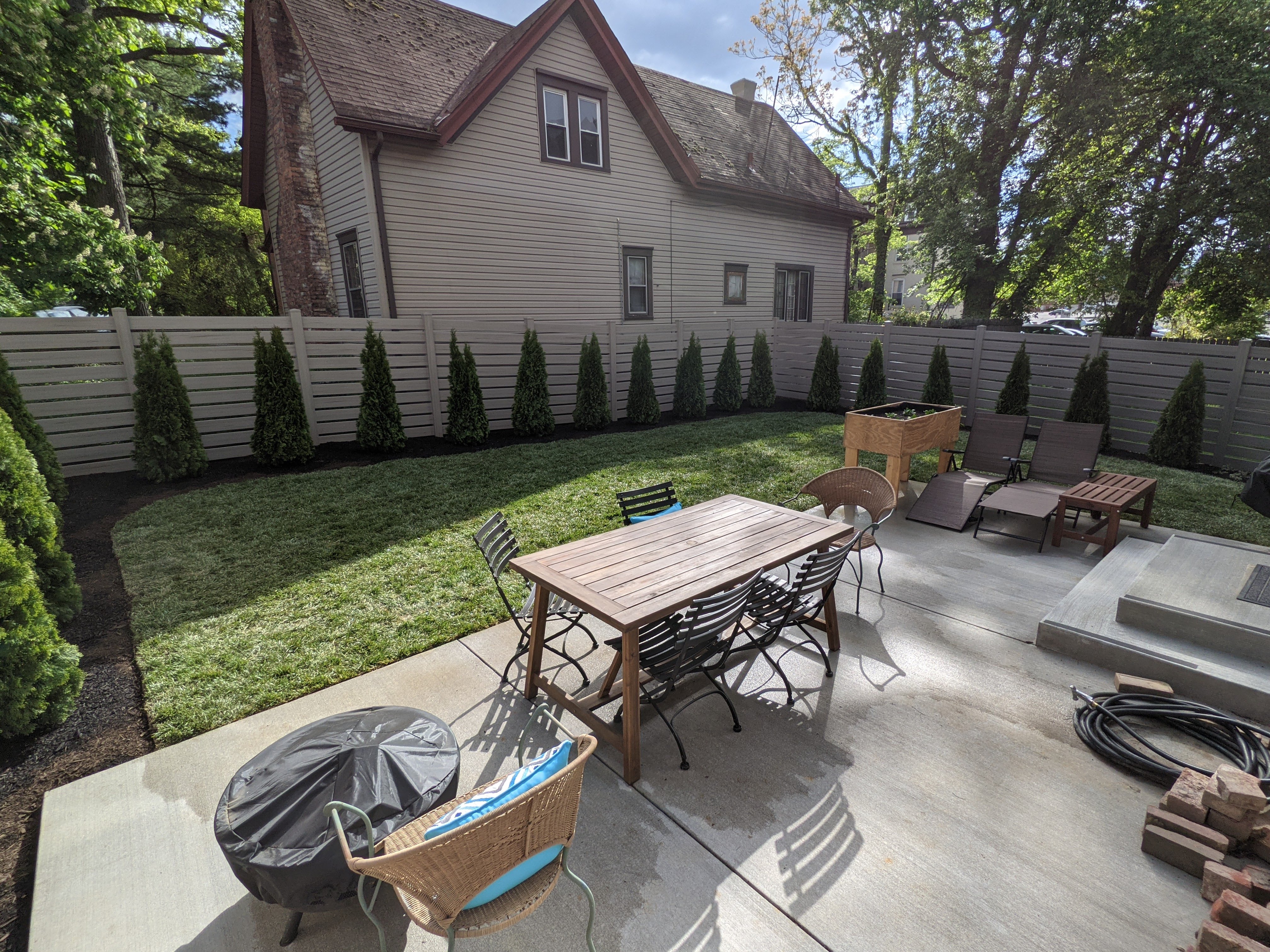 Outdoor patio with table, chairs, and lounge chairs in a backyard.