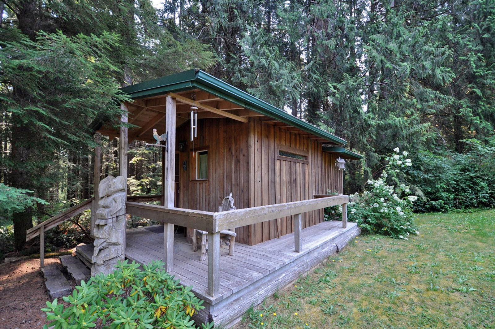 Cozy wooden cabin surrounded by lush trees and greenery.