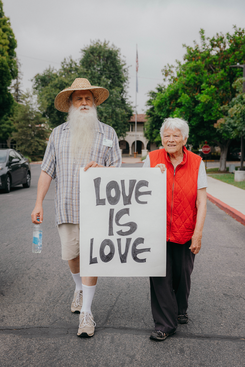 Elderly couple holding a 'Love is Love' sign during community march.