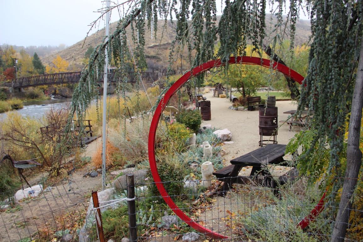 Outdoor community space with seating, plants, and a red circular sculpture.
