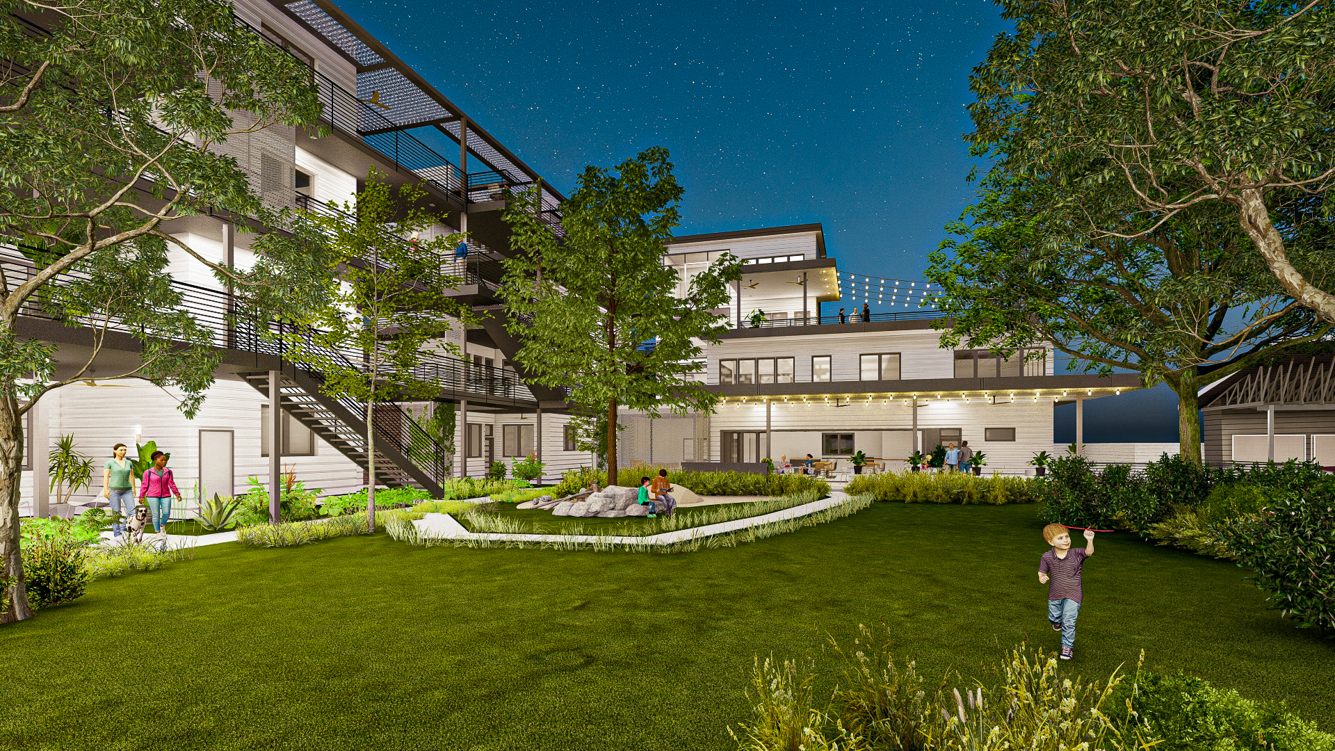 Night view of a modern cohousing community with green lawn and trees.