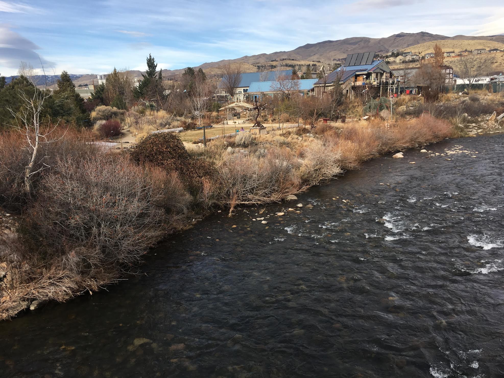 Scenic view of river with community and mountains in the background.