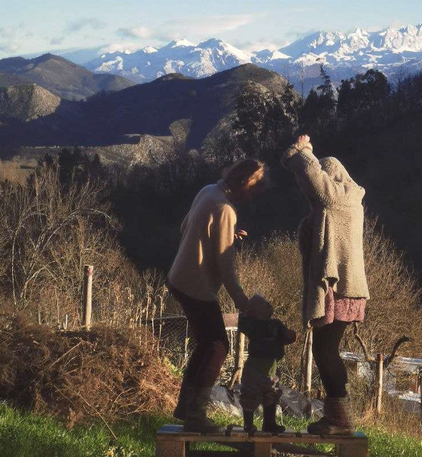 Family with child on a mountain trail with scenic mountain range in background.