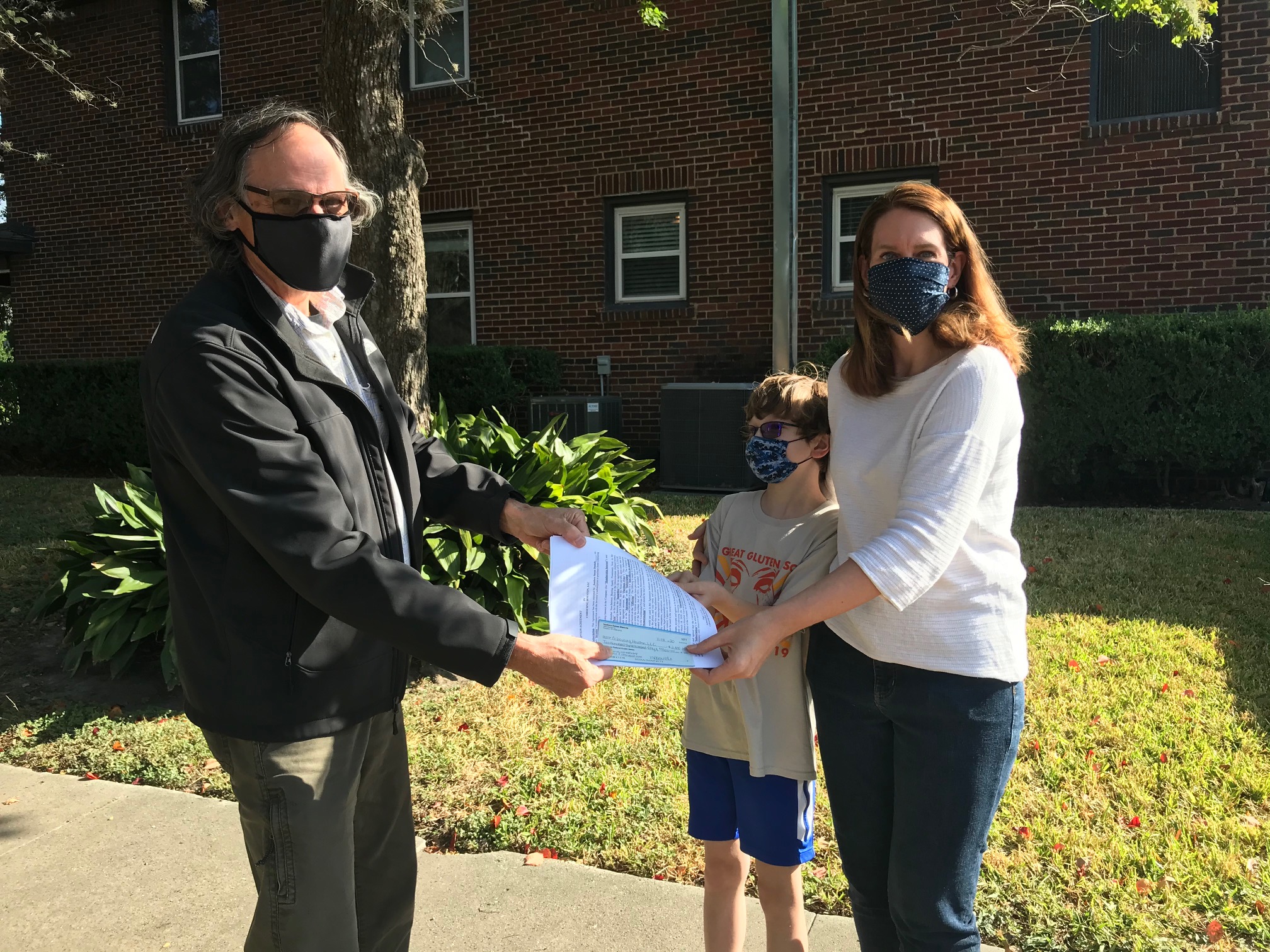 People wearing masks exchanging documents outdoors in CoHousing Houston.