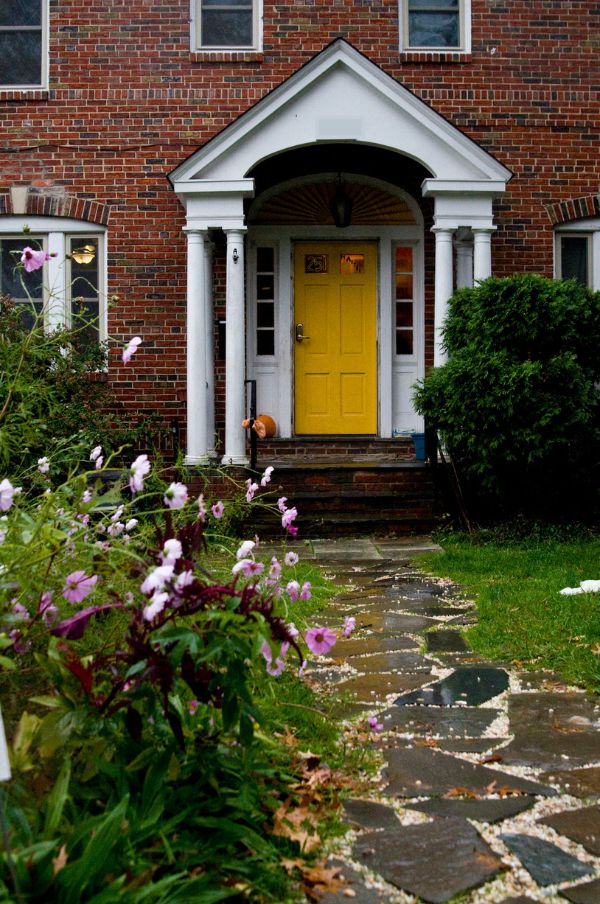 Colorful house entrance with yellow door and garden path.