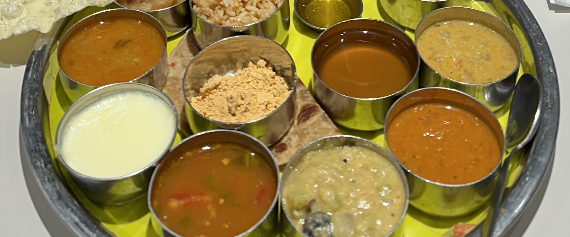 Assorted Indian curries served in small bowls on a round tray.