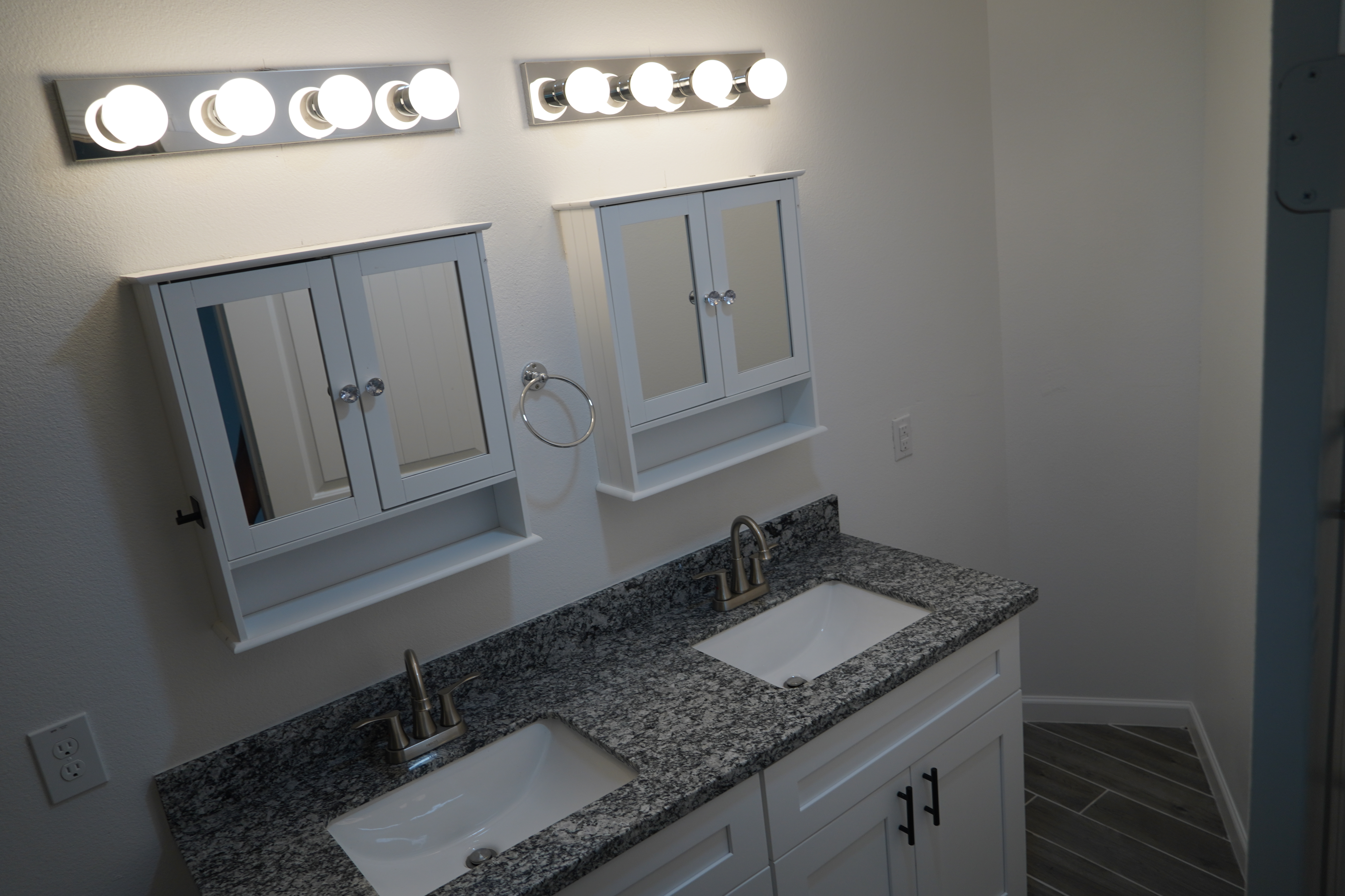 Contemporary bathroom with dual sinks, granite countertop, and bright lighting.