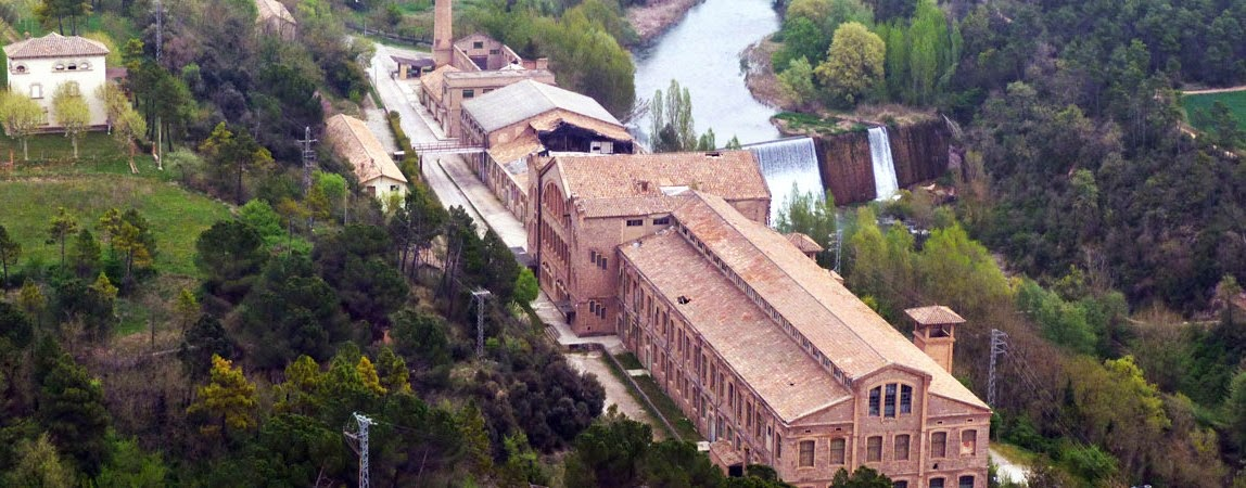 Aerial view of a historic community center surrounded by lush greenery and water features.