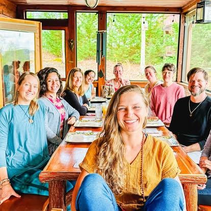 Group of diverse people enjoying a meal together in a cozy, natural setting.