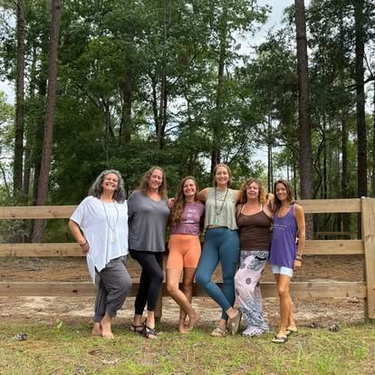 Women standing together in a forest, smiling and enjoying nature.