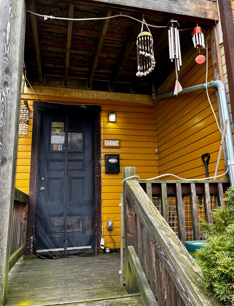 Entrance to Foundation for Intentional Community with wind chimes and yellow siding.