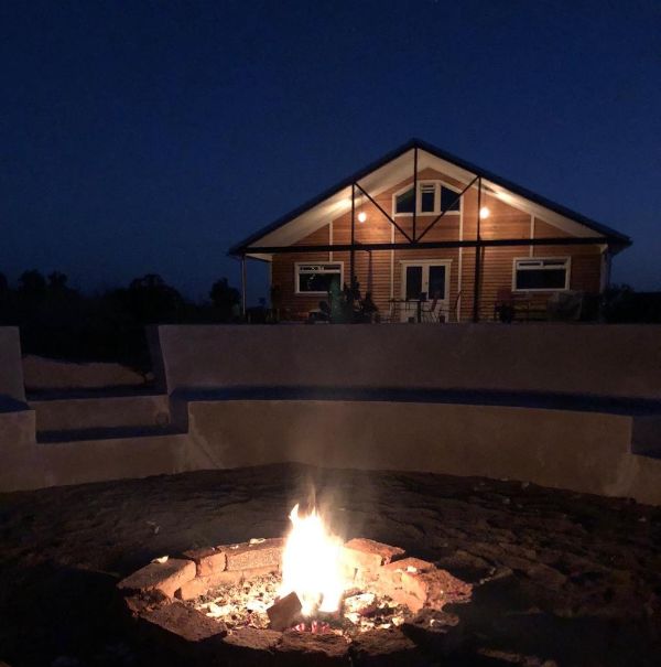 Night view of eco community house with fire pit in foreground.