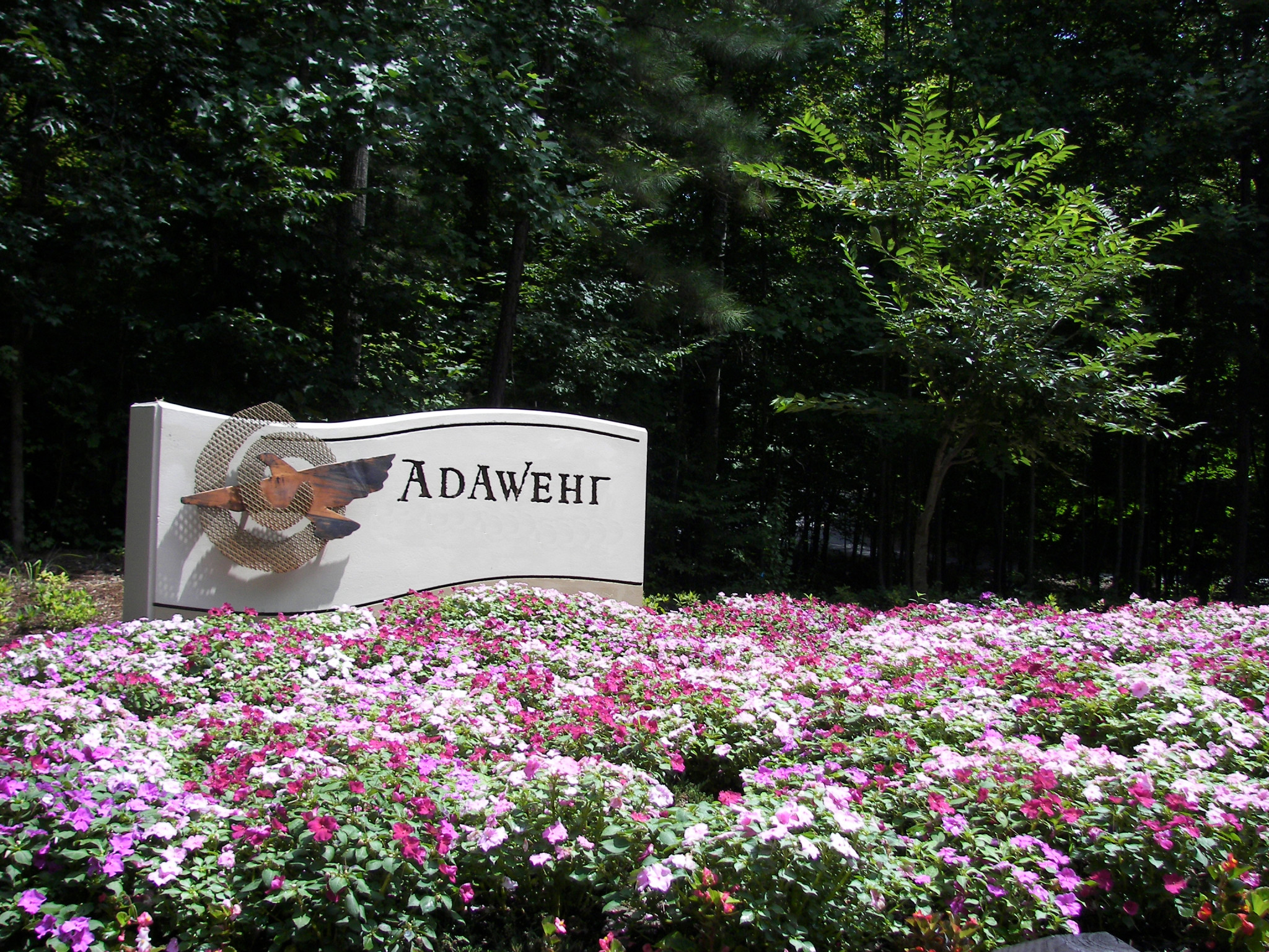 Foundation for Intentional Community sign surrounded by colorful flowers and trees.