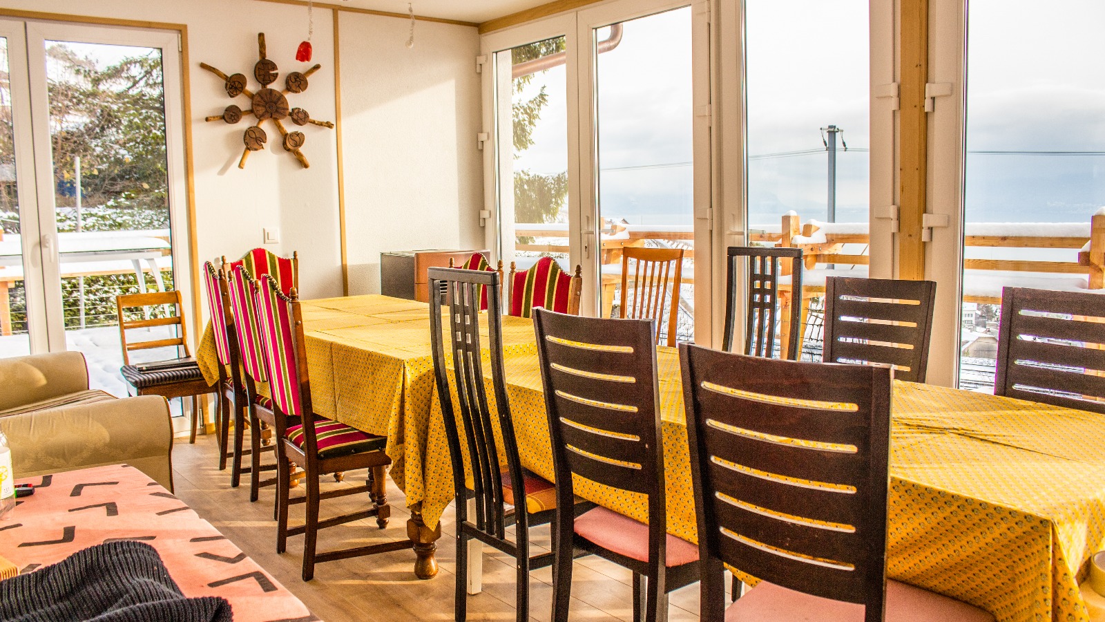 Interior of a dining room with a long table, colorful chairs, and ocean view.