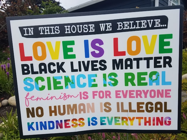 Colorful sign with messages of love, equality, and social justice at community event.