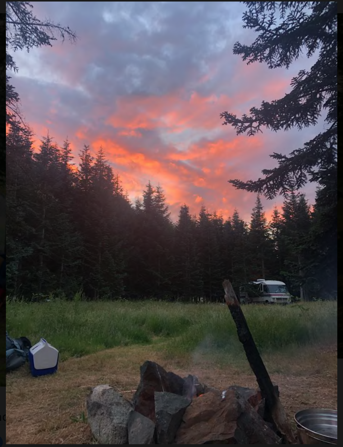 Beautiful sunset with pink and orange clouds over a forest campsite.