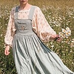 Woman holding daisies in a field of wildflowers for community project.
