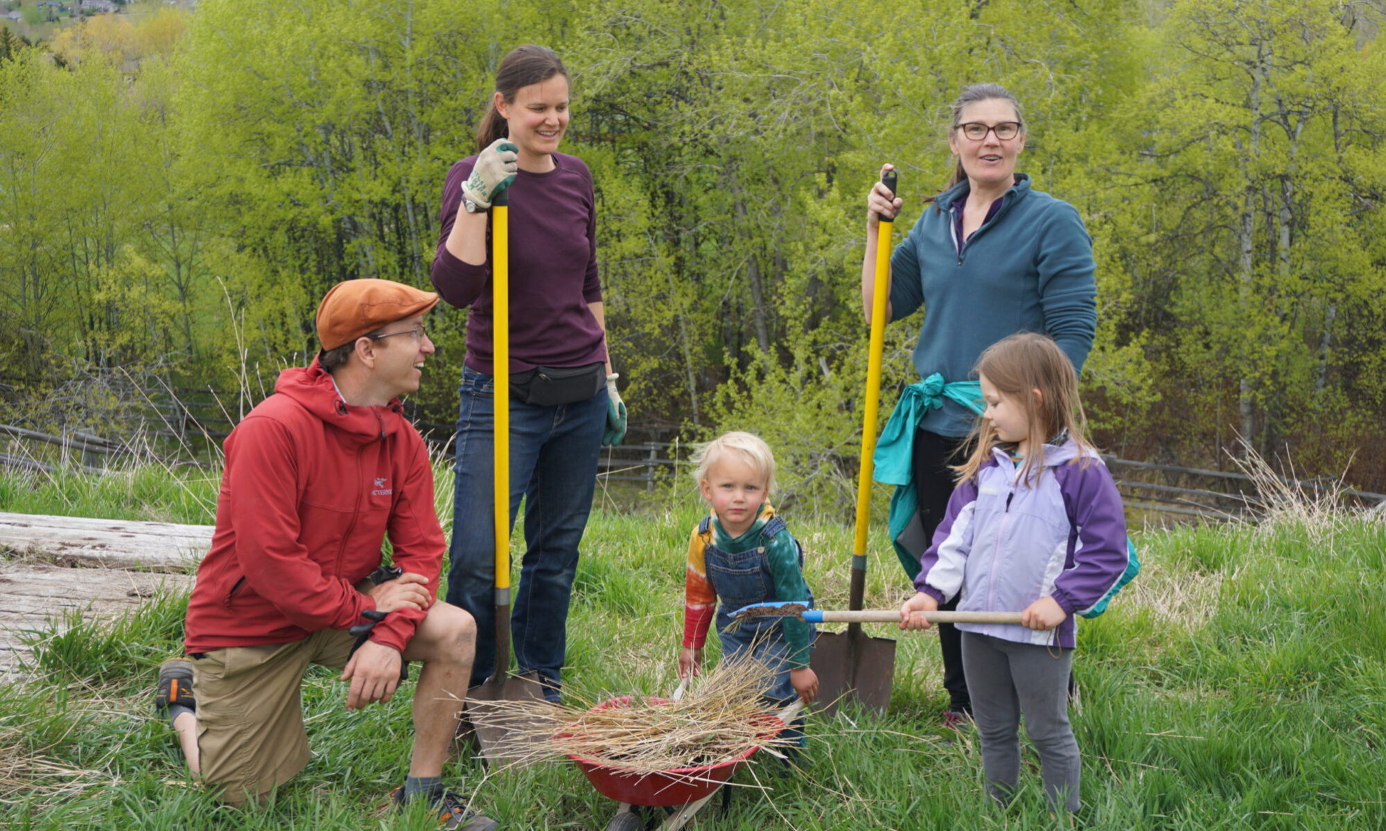 Group of people planting a garden in a green outdoor setting.