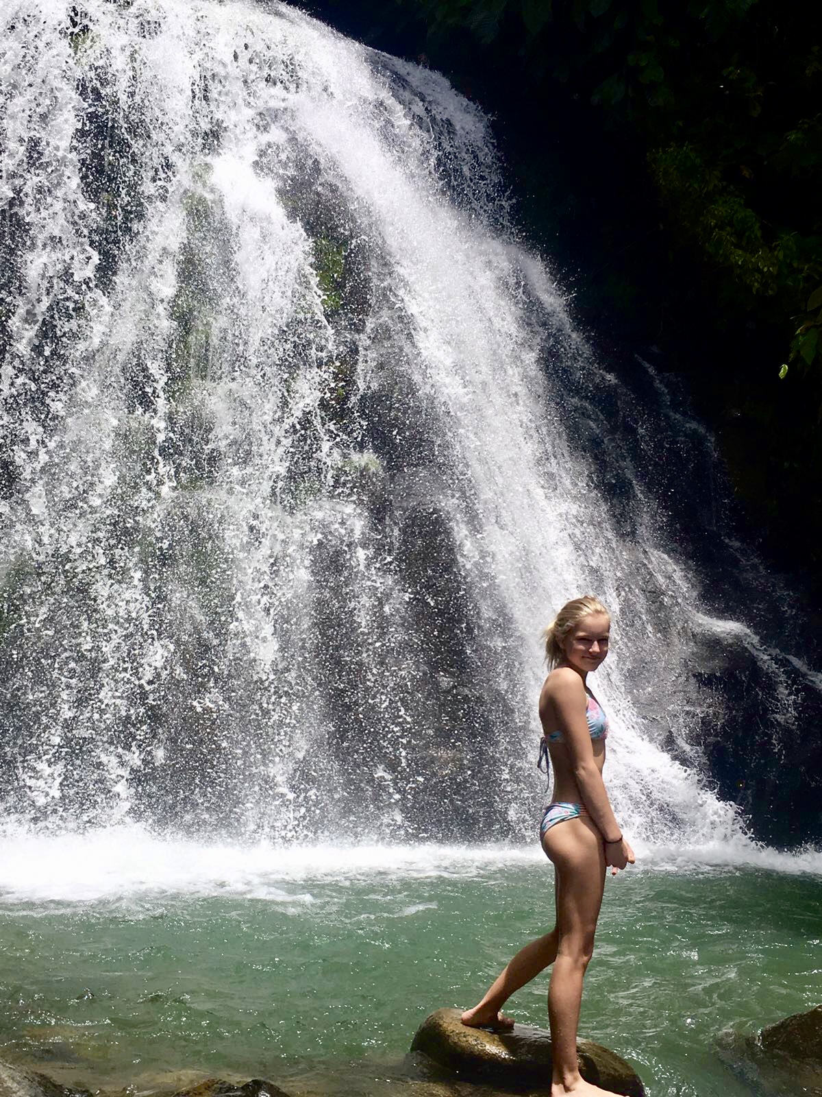 Woman enjoying waterfall at RiverFalls Village in a swimsuit.