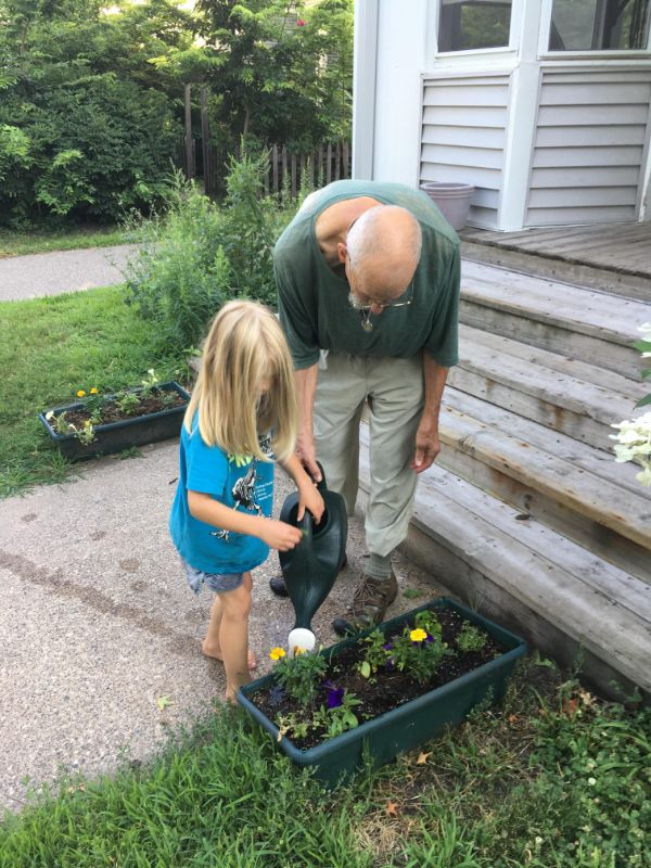 Adult and child watering plants in a community garden at Twin Cities Cohousing.