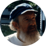 Portrait of a man with a beard and cap, outdoors, representing community building.