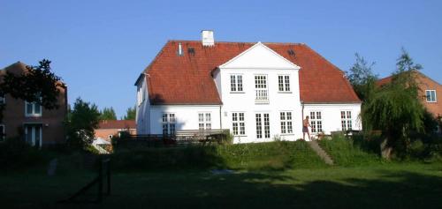 White house with red roof and green lawn at Ibsgården community.