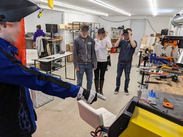 People exploring a MakerHouse workshop with tools and equipment.