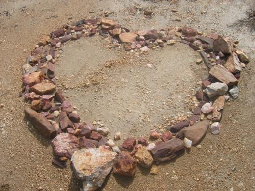 Heart-shaped stone arrangement on sandy ground for community or nature symbolism.