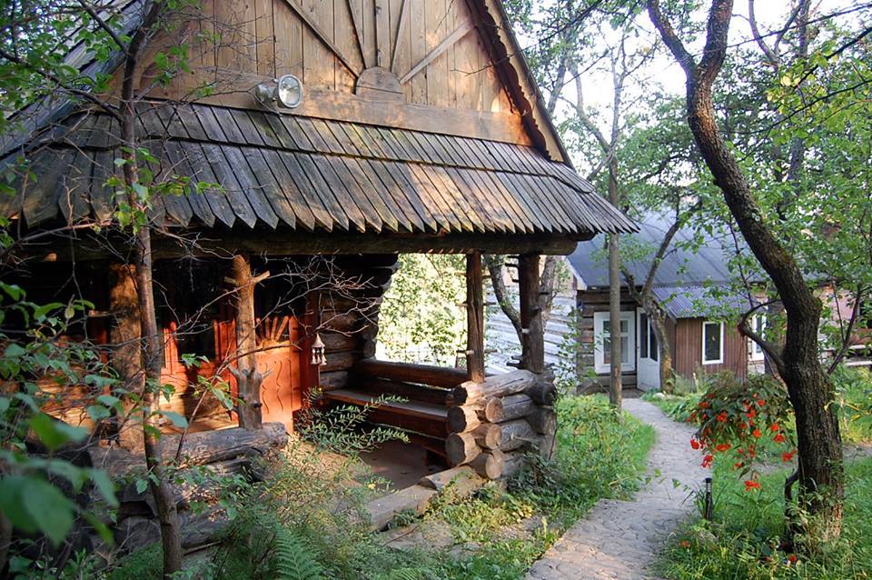 Rustic wooden cabin in a lush green eco-village setting.