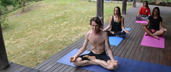 People practicing yoga outdoors on a wooden deck at Nymboida Yoga Retreat.